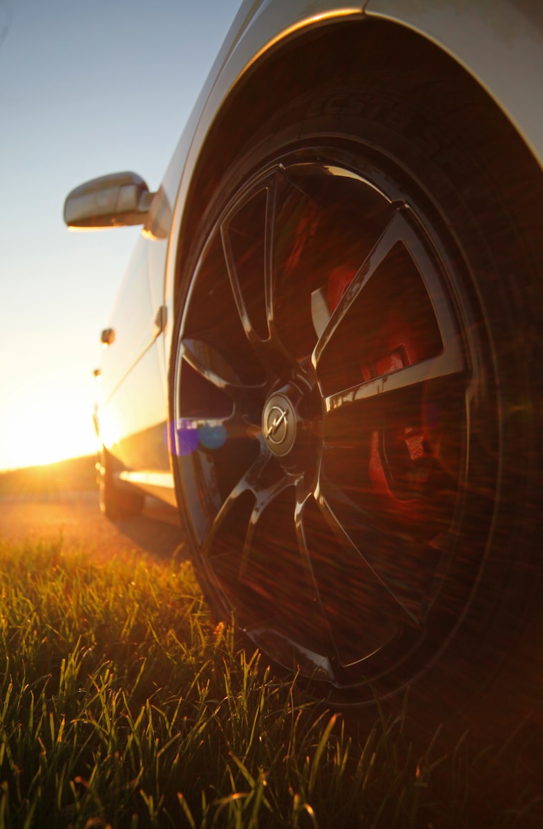 Photo by Robert Klank black and red car wheel on green grass during sunset